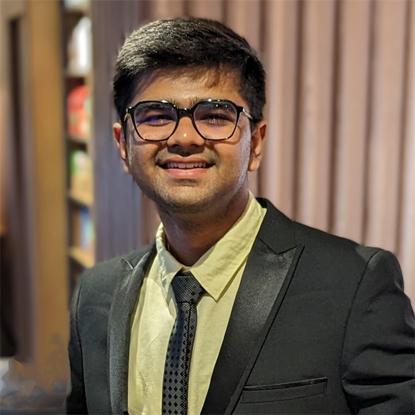 Jay Dave wearing glasses and smiling at the camera in a green suit